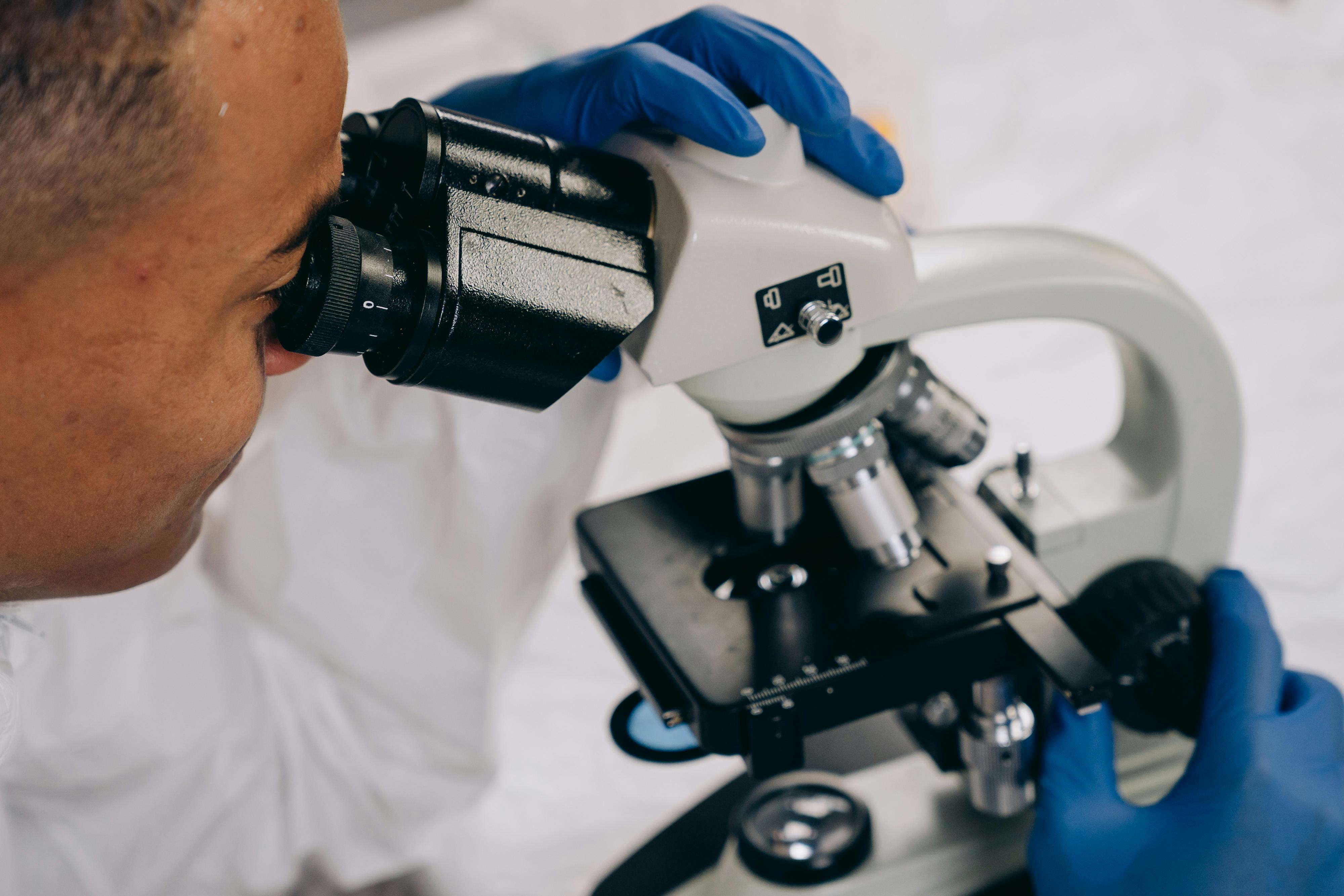 Laboratory technician in protective gloves carefully analyzing blood samples under bright clinical lighting